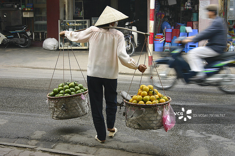 后视图的一个女人卖水果，河内，越南图片素材