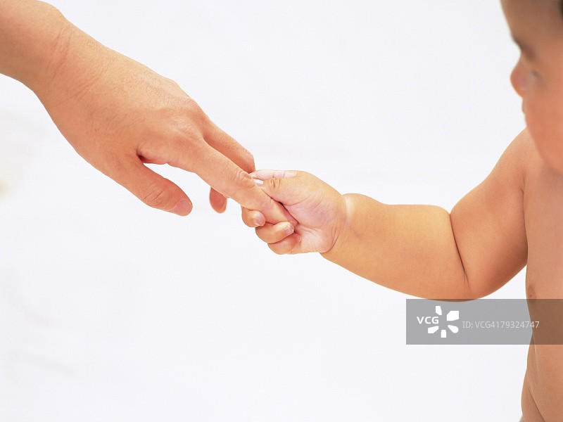 婴儿抱着妈妈的手指，侧视图片素材