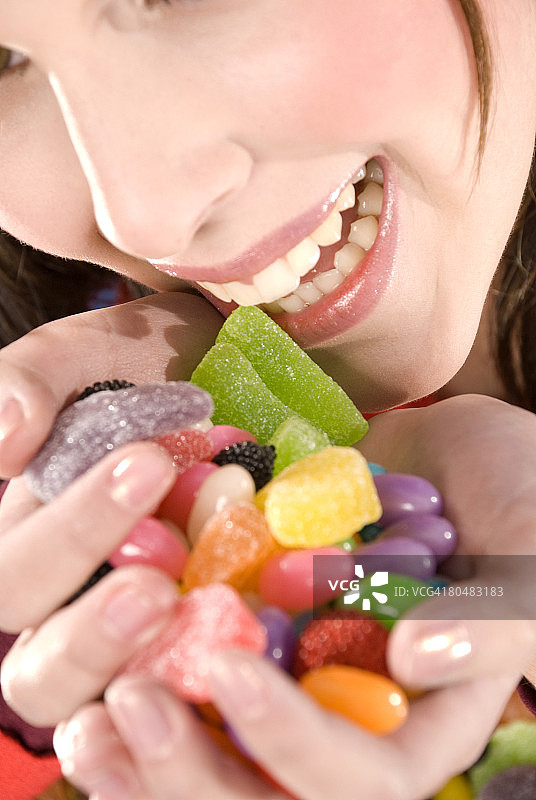 女人拿着一把糖果，特写镜头，微笑着图片素材
