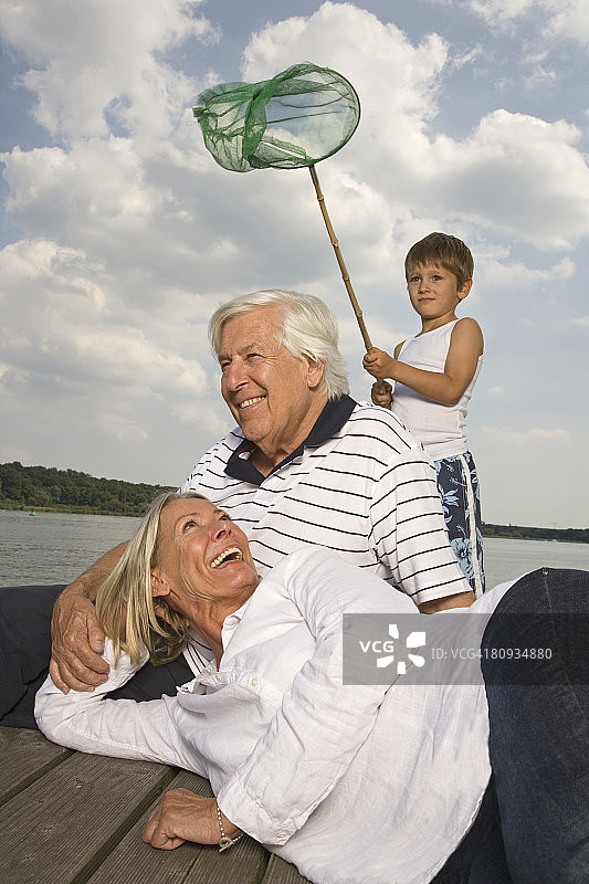 快乐的祖父母和孙子在湖边图片素材