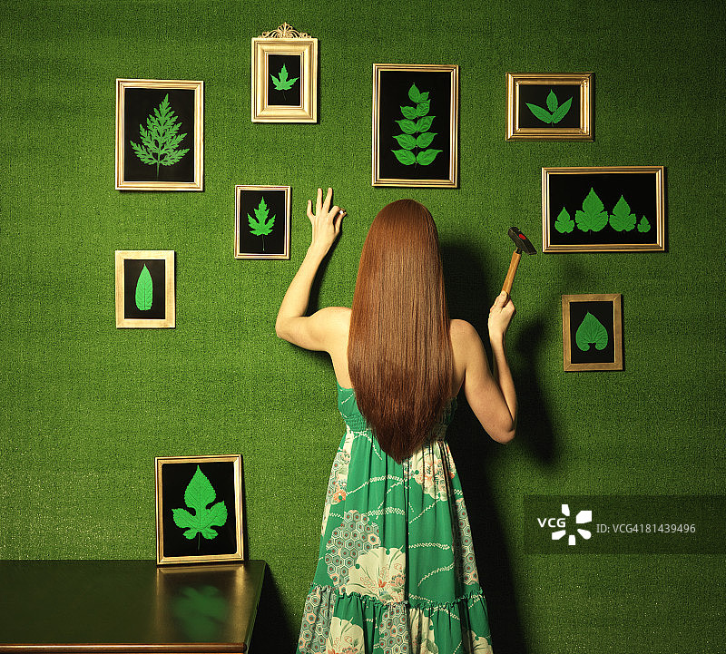 一个女人在休息室的墙上挂着树叶的画。图片素材