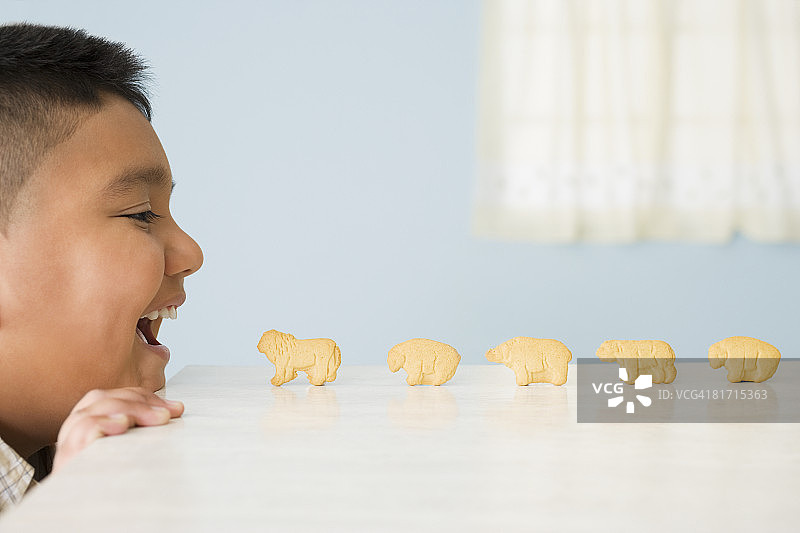 动物饼干在西班牙男孩的嘴巴前排成一排图片素材