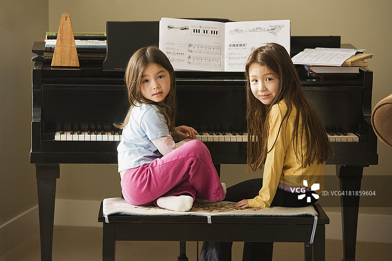 亚洲姐妹坐在钢琴前图片素材