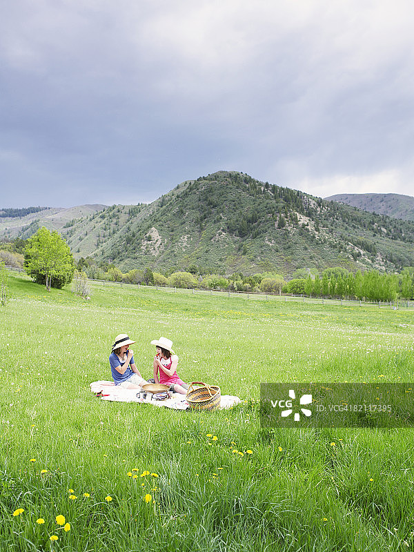 两个十来岁的女孩在草地上野餐。图片素材