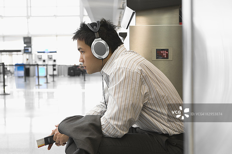 一个在机场听耳机的商人的侧影图片素材