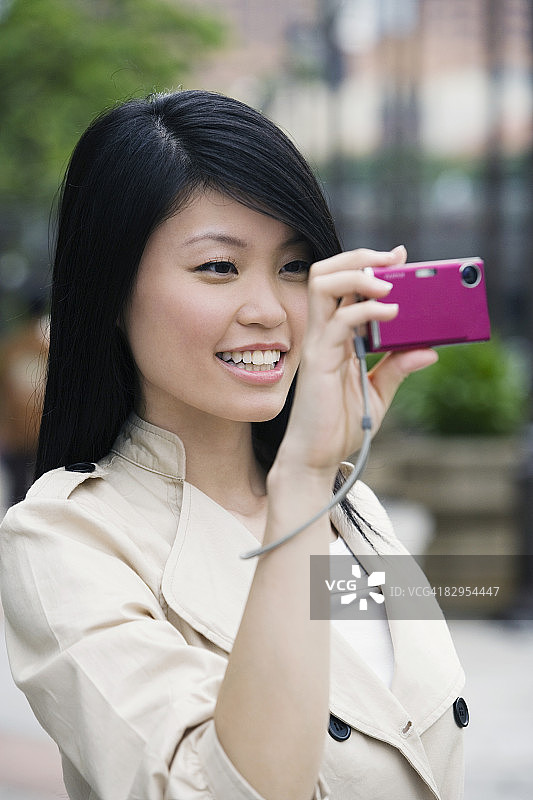 一个年轻女子用数码相机拍照的特写图片素材