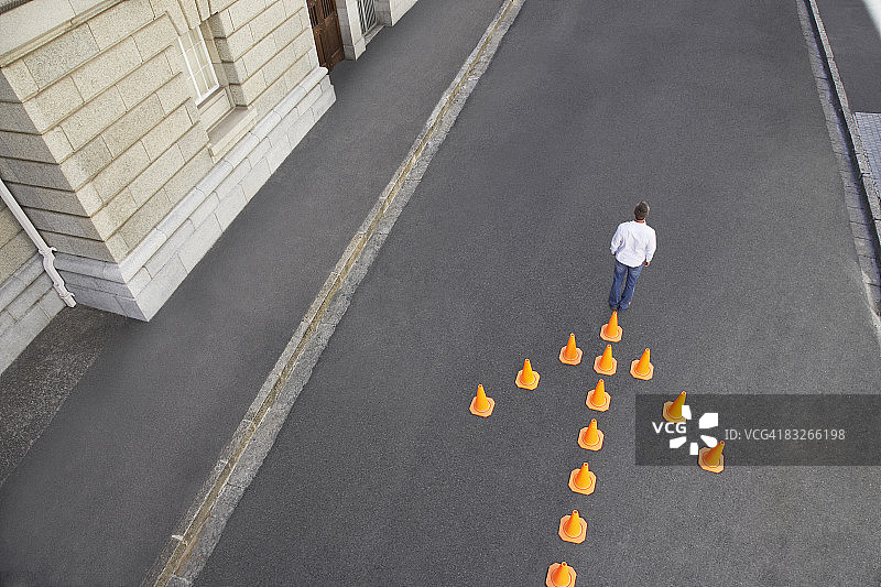 一名男子站在箭头形状的交通锥前图片素材