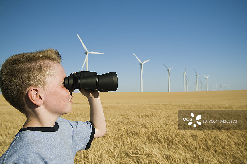风电场上的男孩用双筒望远镜看图片素材