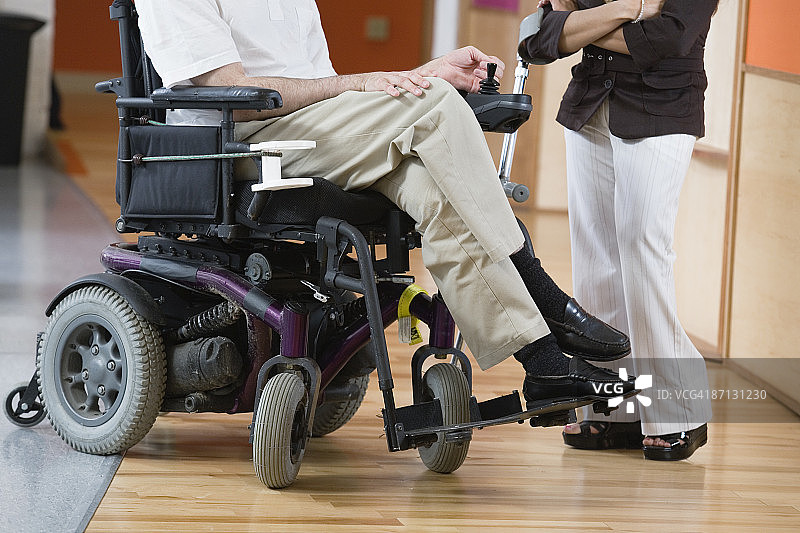 一个坐轮椅的残疾人和拄着拐杖的妇女。图片素材