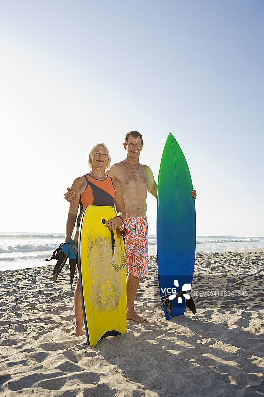 一对退休夫妇在海滩上玩冲浪板图片素材