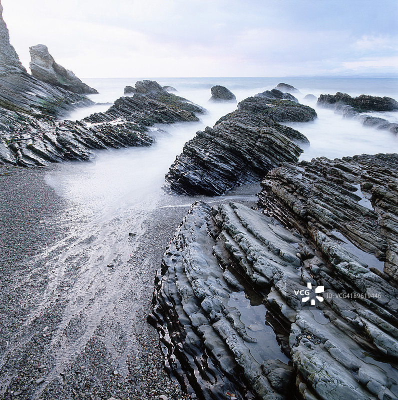 海浪冲击着海滩上的岩层图片素材