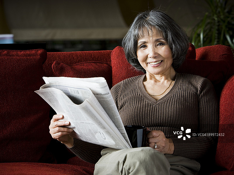 老妇人坐在沙发上看报纸图片素材