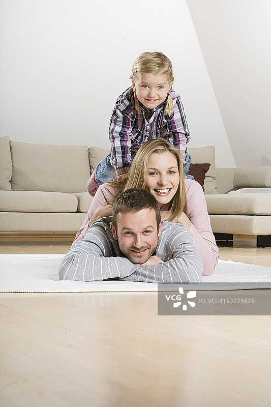 父母和女儿(3-4)在地毯上放松，人像图片素材