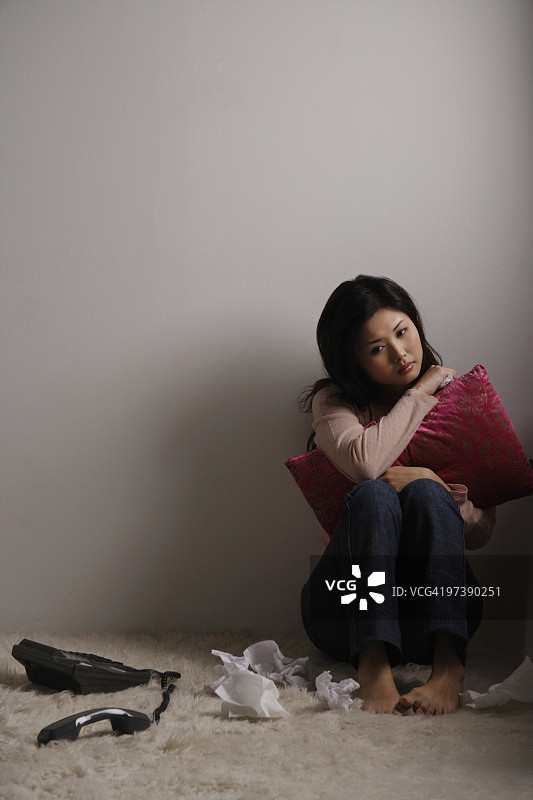 一个中国女人坐在地板上，看起来很伤心图片素材