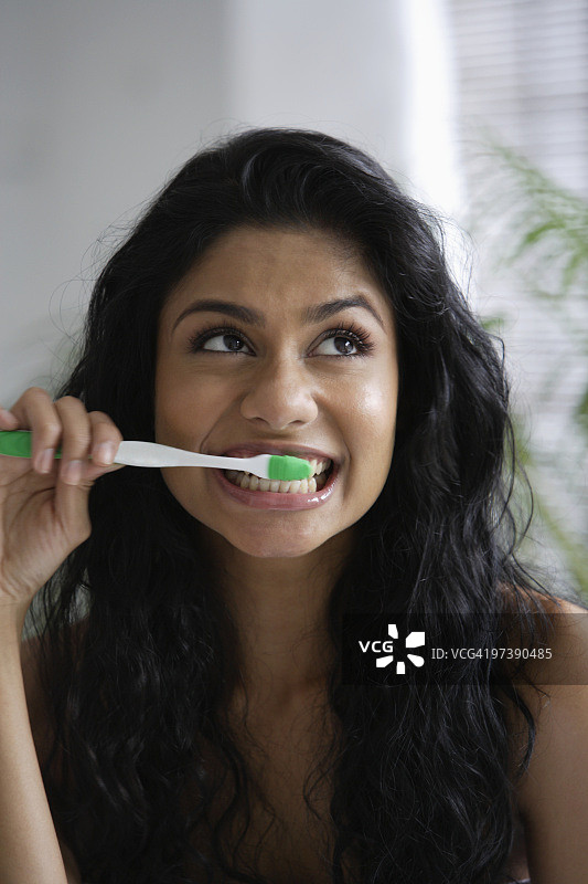 一名印度妇女正在刷牙，抬头看图片素材