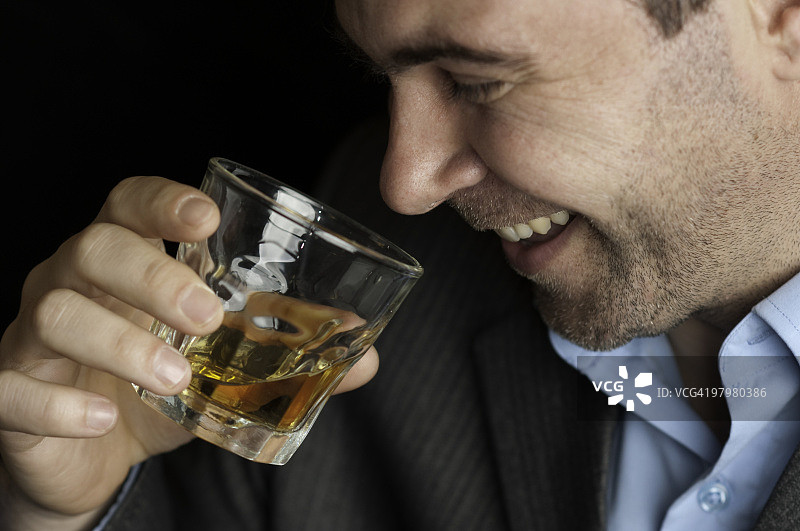 一个男人喝着玻璃杯里的威士忌图片素材