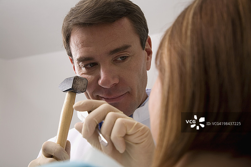 牙医用锤子和凿子治疗女性病人图片素材