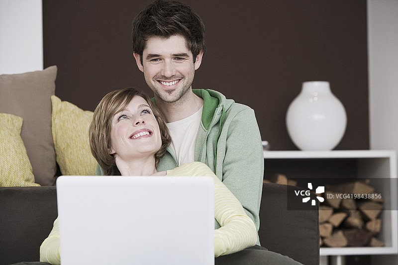 年轻夫妇在家里一起用笔记本电脑工作图片素材