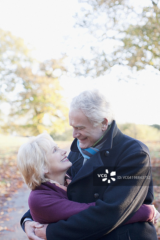一对老年夫妇在秋天的户外拥抱图片素材