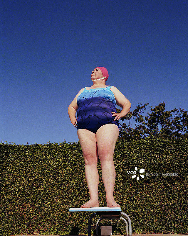 身着泳装的女子站在跳水板上，低角度观看图片素材