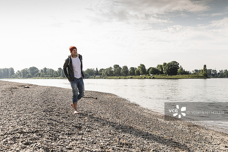 戴着红色帽子的成熟男子漫步在莱茵河岸边图片素材