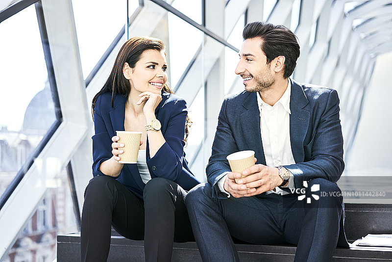 微笑的女商人和在现代办公室里喝咖啡的商人图片素材