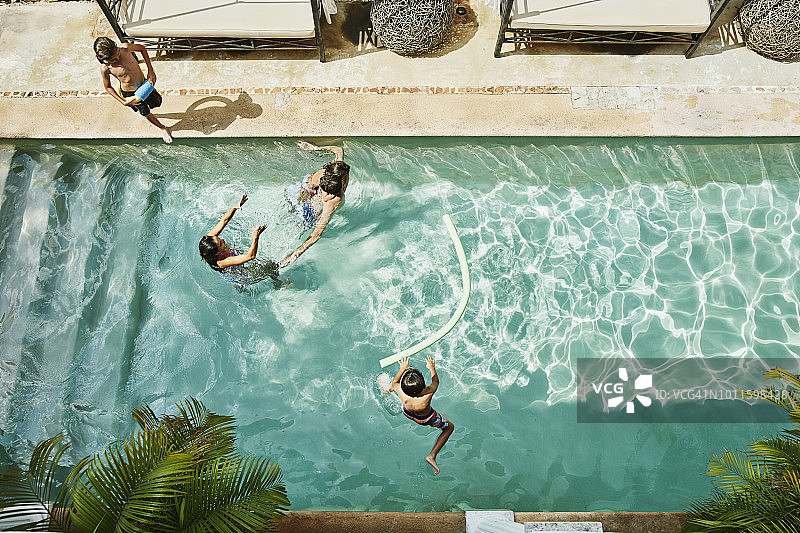 俯瞰家庭一起在热带度假村的游泳池里玩耍图片素材