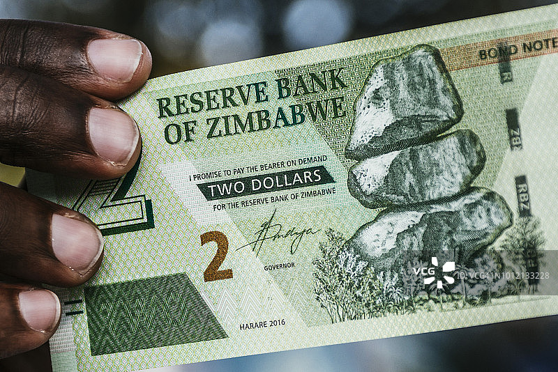 一名男子持有津巴布韦两美元债券钞票图片素材