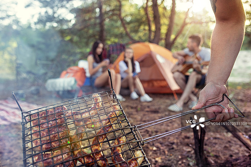 聚会，男女团体露营在森林。他们放松，唱歌，做烧烤图片素材