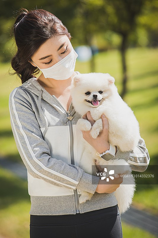 戴着防尘面具，抱着一只狗的女人图片素材