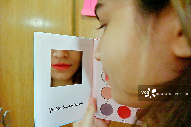 一个女孩在化妆，看着梳妆镜的特写图片素材