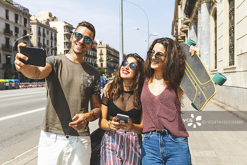 三个快乐的朋友在城市里自拍图片素材
