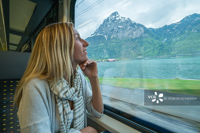 在瑞士乘火车旅行的年轻女子透过窗户看图片素材