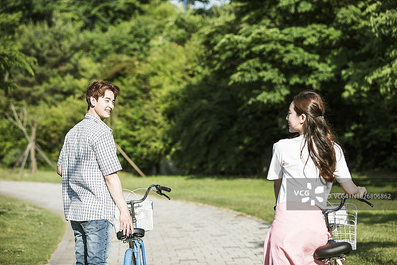 一对学生情侣在公园里骑自行车图片素材