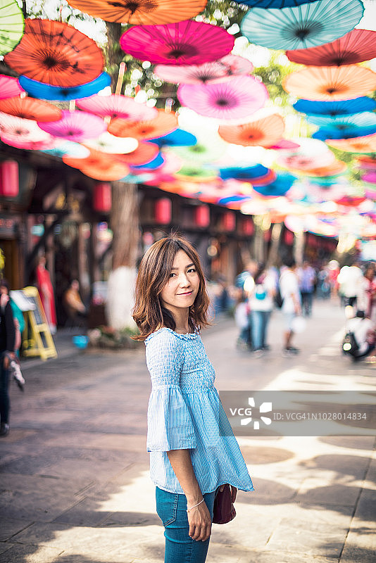 美丽的中国女子站在中国古镇的街道上图片素材
