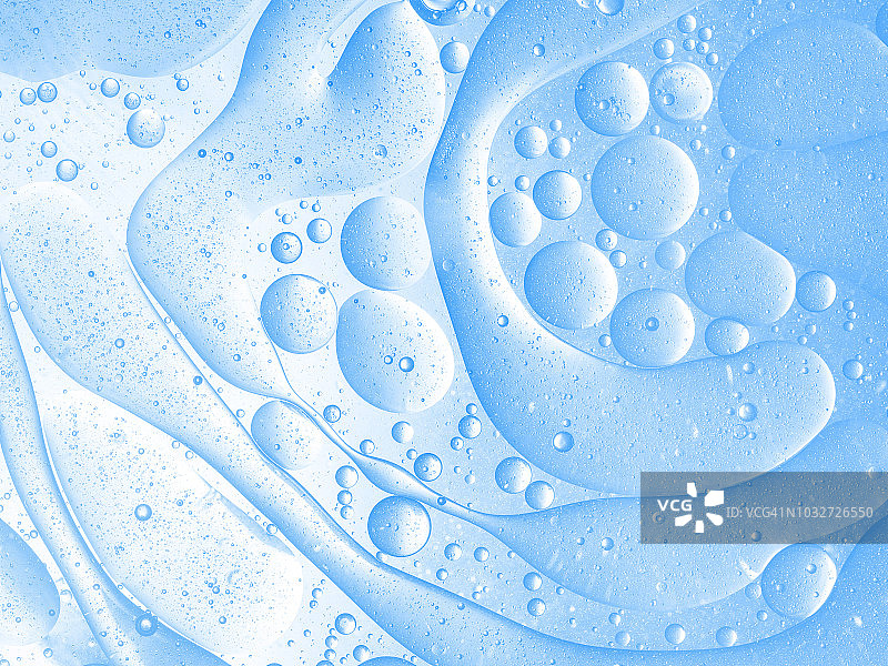 全框架的抽象形状和纹理，形成的气泡和水滴在一个柔和的蓝色液体背景。图片素材