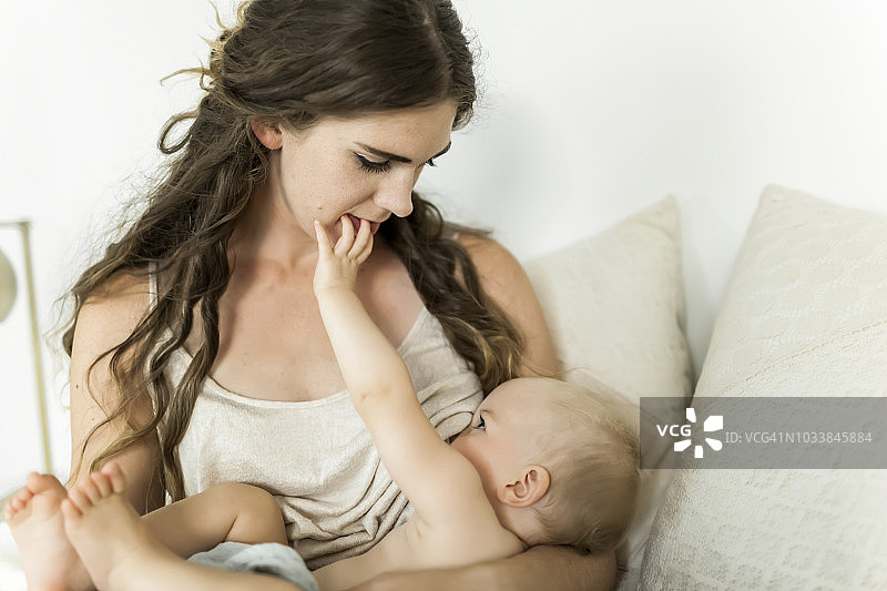 一位母亲抱着她的小女婴，在床上给她喂奶图片素材
