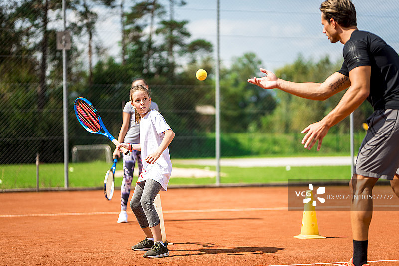 一个年轻人教两个女孩打网球图片素材