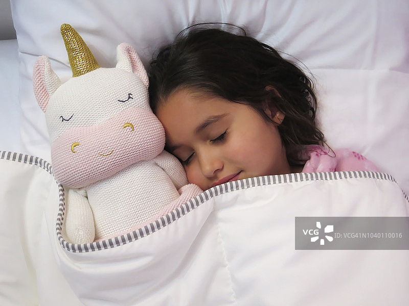 年轻女孩和她的独角兽睡觉。图片素材