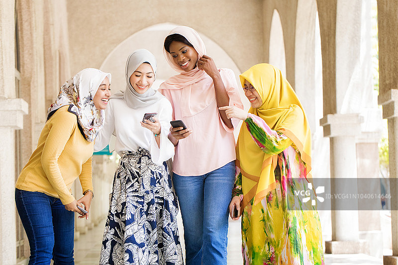 一小群穆斯林女大学生在手机上嘲笑媒体图片素材