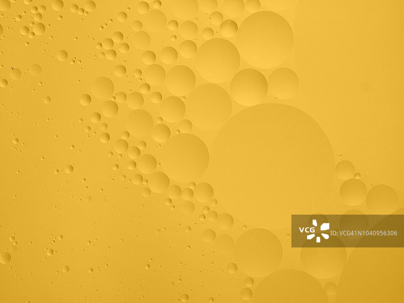 全框架的抽象形状和纹理，形成的气泡和液滴在柔和的黄色液体背景。图片素材