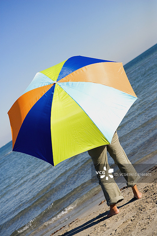 一个人带着雨伞站在沙滩上的后视图图片素材