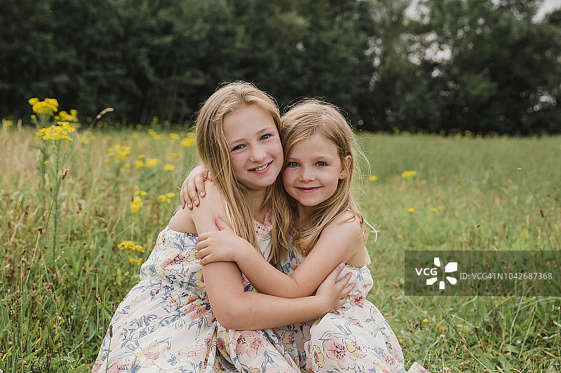两个小妹妹在草地上互相拥抱图片素材
