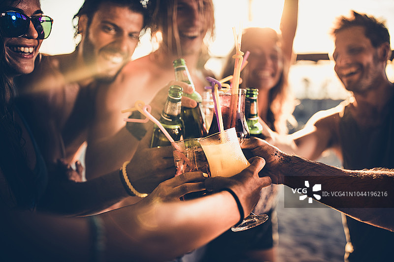 快乐的朋友在日落时喝酒的特写。图片素材