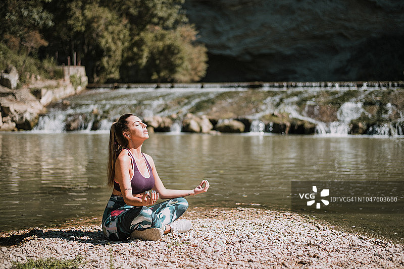 一个年轻女子在河边练瑜伽图片素材