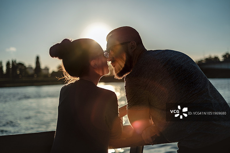 日落时分，一对相爱的情侣在河边接吻图片素材