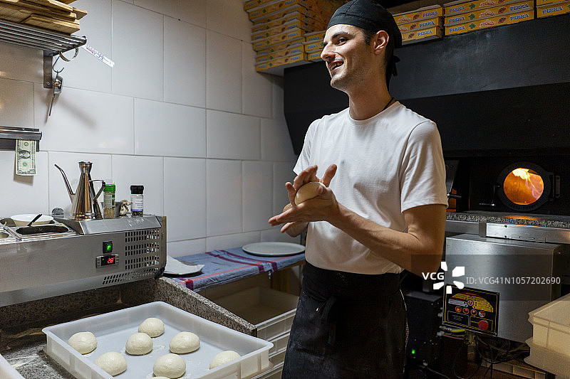 微笑的披萨面包师在厨房塑造面团图片素材