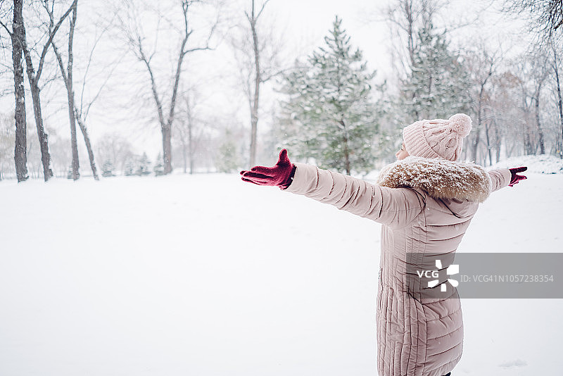 一个女人在白雪覆盖的公园里摊开双手图片素材