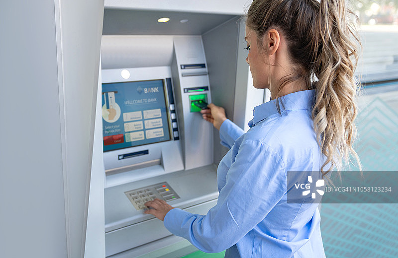 快乐的女人在自动取款机上取钱图片素材