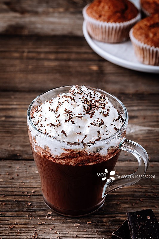 热巧克力饮料与掼奶油在一个玻璃杯在木背景图片素材